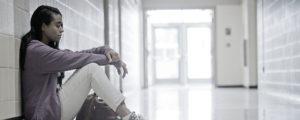 Girl Sitting Against Lockers