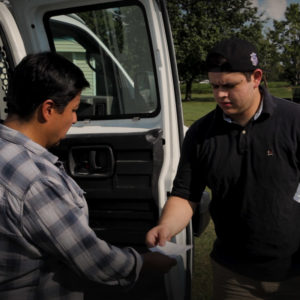 Man handing a slip of paper to another man